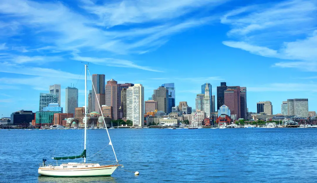Boston harbor with sailboat and city skyline on a clear blue day